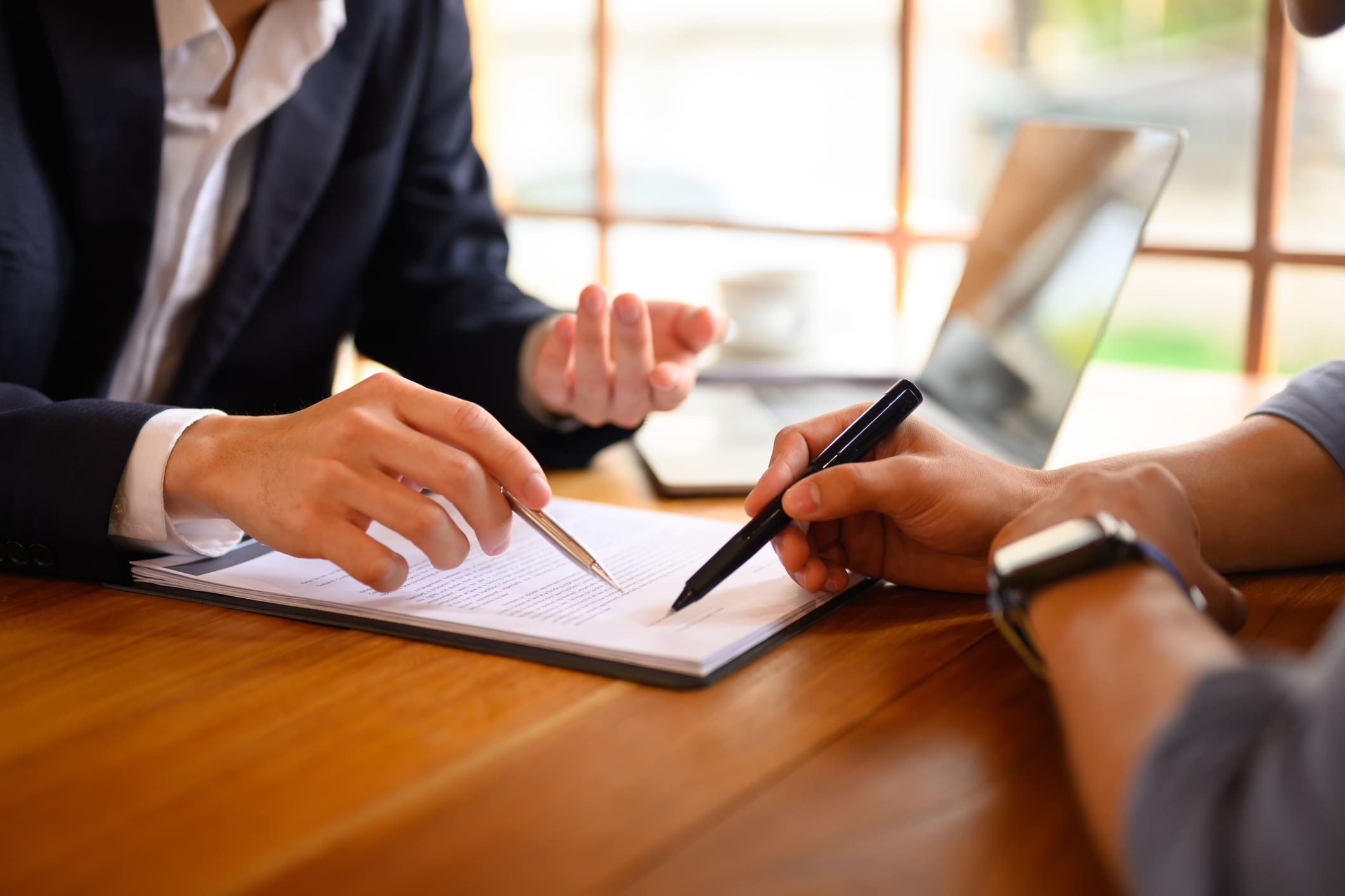 Closeup lawyer or insurance agent pointing at contract showing male client where to signature sign.